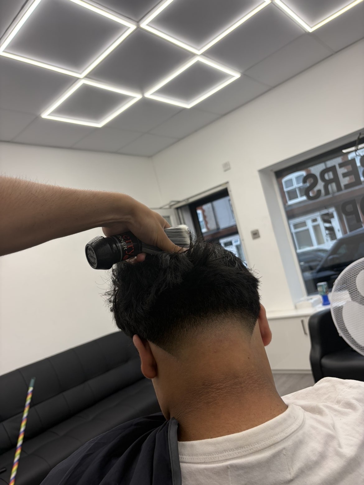 Barber finishing a skin fade with cologne spray